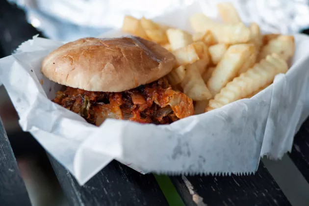 En hamburgare och pommes ligger i en skål täckt med bakplåtspapper.