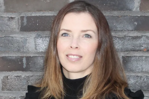 Bild på Elin Östlinds ansikte mot en tegelbakgrund