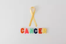 Foto på ett gult sidenband med färgglada plastbokstäver undertill som stavar ordet cancer